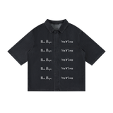 Front view of washed black short-sleeve lyocell shirt with white New York and inverted Pizdets lettering