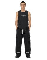 Model wearing black MIROLYUB Wordmark side-stripe pants with a black raw-hem tank.