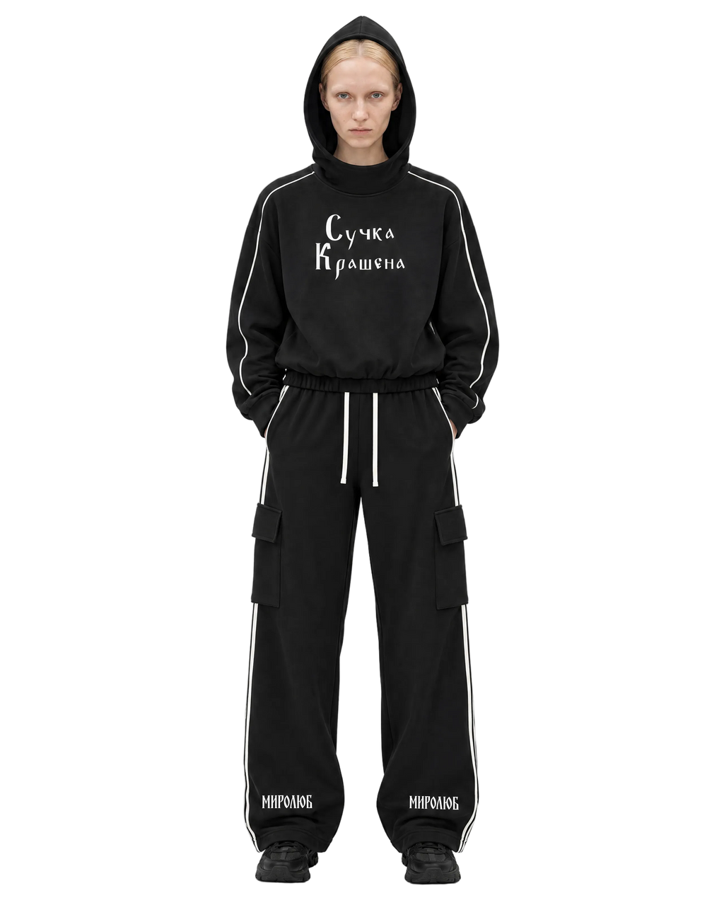 Model wearing a black MIROLYUB Suchka Krashena piping hoodie and black Wordmark side-stripe pants.