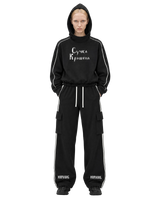 Model wearing a black MIROLYUB Suchka Krashena piping hoodie and black Wordmark side-stripe pants.