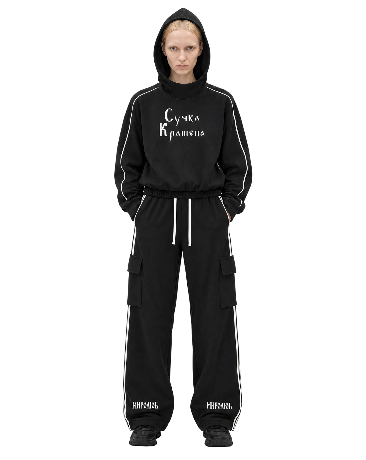 Model wearing a black MIROLYUB Suchka Krashena piping hoodie and black Wordmark side-stripe pants.