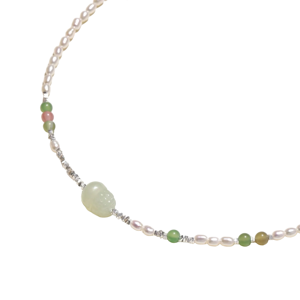 Angled detail of Zdravka necklace showing freshwater pearls, coloured stone beads and a pale green carved centre