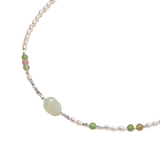 Angled detail of Zdravka necklace showing freshwater pearls, coloured stone beads and a pale green carved centre